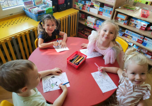 Czworo dzieci siedzących przy czerwonym stole