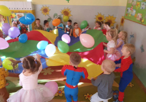 Dzień Postaci z Bajek - dzieci trzymają chustę animacyjną i kołyszą balony