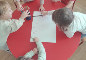 Dzieci w małych zespołach rysują wspólny obrazek kredkami