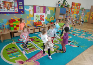 Dzieci tańczą na dywanie ze swoimi przytulankami