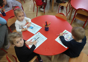 Kolorowanie przez dzieci obrazków skarpet przy stolikach