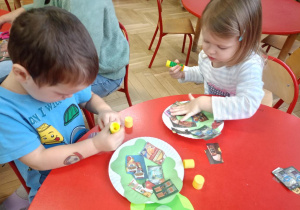 Dzieci przy stoliku wykonują pracę plastyczną ,,Talerzyki pełne zdrowia"