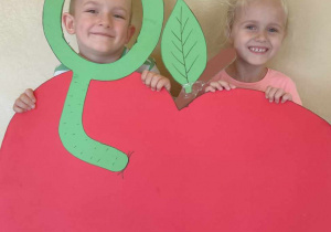 dwoje dzieci trzymające szablon dużego jabłka