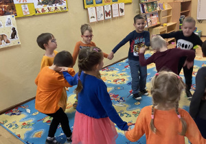 Dzieci tańczące w kole na kolorowym dywanie