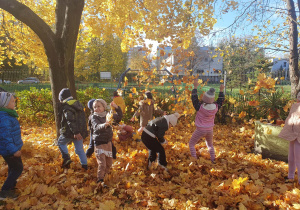 Dzieci bawią się w ogrodzie liśćmi