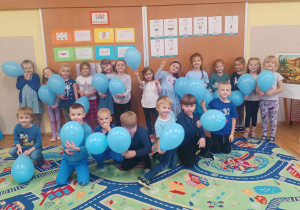 Grupa dzieci trzyma niebieskie balony, które są symbolem obchodzonego Dnia Praw Dziecka