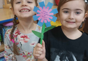Dwie dziewczynki pozują do zdjęcia prezentując kwiatek wykonany z okazji Dnia Życzliwości