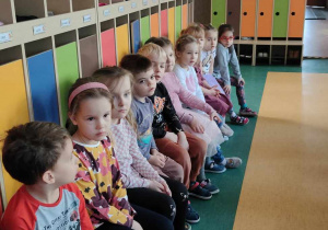 Dzieci siedzące ławkach przy kolorowych szafkach