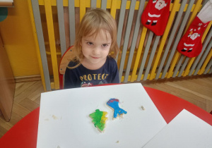 Dziewczynka pozuje ze stworzonymi przez siebie pierniczkami z masy solnej
