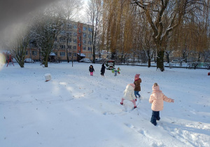 Dzieci biegają po śniegu w ogrodzie przedszkolnym