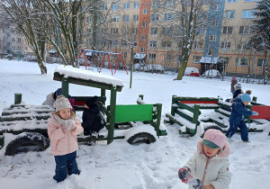 Dzieci bawią się w drewnianej ciuchci obsypanej śniegiem