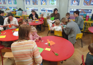 Warsztaty z rodzicami - rodzice wraz z dziećmi siedzą przy stolikach i wykonują kartki dla mieszkańców DPS u