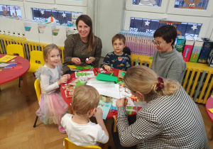 Warsztaty z rodzicami - rodzice wraz z dziećmi siedzą przy stolikach i wykonują kartki dla mieszkańców DPS u