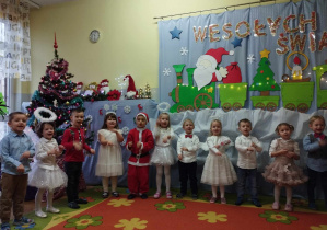 Uroczystość choinkowa - dzieci stoją w półkolu i śpiewają piosenki