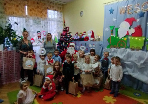 Uroczystość choinkowa - dzieci wraz z św. Mikołajem i nauczycielkami pozują do zdjęcia