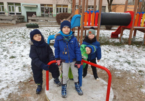 W ogrodzie przedszkolnym - czterech chłopców stoi na urządzeniu ogrodowym