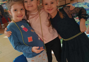 Trzy dziewczynki pozują do zdjęcia w sali przedszkolnej