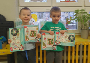 Dwóch chłopców stojących z pudełkami w świąteczne wzory