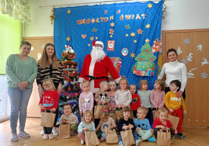 Dzieci, Mikołaj i panie oraz panie na niebieskim tle z ozdobami świątecznymi