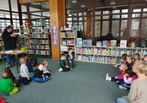 Zajęcia w bibliotece - dzieci słuchają bajki czytanej przez bibliotekarza