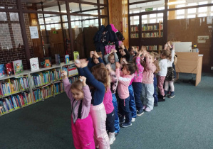 Zajęcia w bibliotece - dzieci ustawione w pociąg podnoszą ręce do góry