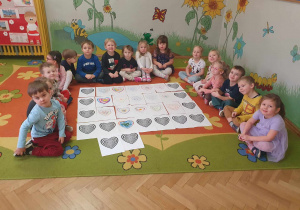 Zabawa sztuką -Op-art, dzieci siedzą na dywanie obok swoich serduszkowych prac