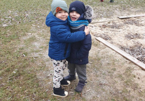 Zabawy w ogrodzie przedszkolnym - dwoje dzieci przytula się do siebie