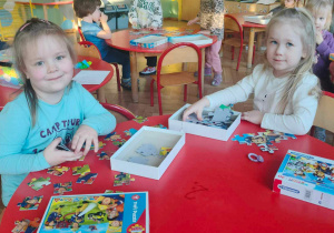 Dwie dziewczynki układają przy stole puzzle