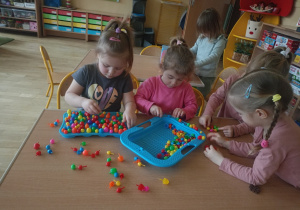 Cztery dziewczynki bawią się przy stole kolorowymi grzybkami