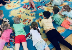 dzieci leżące w kole na niebieskim dywanie