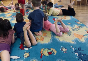 dzieci przebrane w stroje gimnastyczne bawią się na niebieskim dywanie