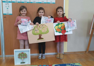 Trzy dziewczynki prezentują swoje prace, dyplomy i nagrody z konkursu Drzewo genealogiczne mojej rodziny