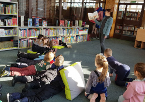 Warsztaty w bibliotece - dzieci słuchają opowiadania.
