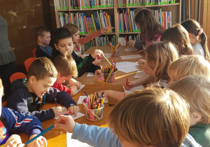 Warsztaty w bibliotece - dzieci wykonują rysunek inspirowany opowiadaniem.