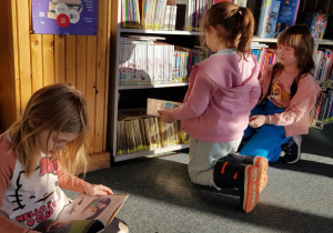 Warsztaty w bibliotece - dzieci oglądają wybrane książki.