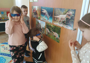 Dzieci oglądają ilustarcję dinozaurów z wykorzystaniem okularów 3D