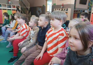 Grupa dzieci ogląda teatrzyk wystawiany w holu przedszkola