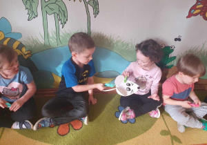 Dzień Kota - dzieci siedzą na dywanie i podają myszkę za pomocą spinaczy do bielizny