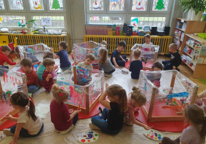 Zabawa sztuką - dzieci siedzą na podłodze i malują farbami na folii, którą owinięte są stoły