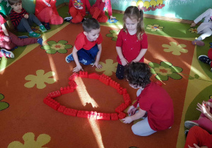 Walentynki - dzieci układają z czerwonych klocków serce na dywanie