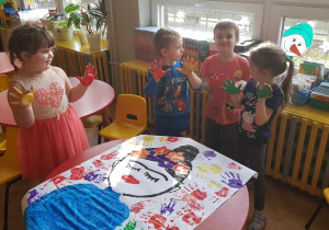 Zabawa sztuką - dzieci wykonują plakat inspiracji odbijając ręce pomalowane farbą