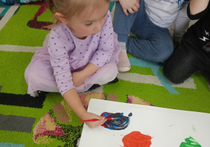 Dziewczynka miesza na kartonie różne kolory farb