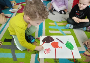 Chłopiec miesza na kartonie różne kolory farb
