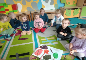 Dzieci siedząc w kole na dywanie obserwują jakie kolory powstały po zmieszaniu różnych ich kolorów