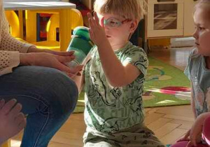 Chłopiec przekręca plastikowy kubek umieszczony w drugim kubku
