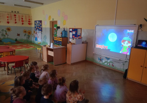 Dzieci oglądają w grupie króliczki film edukacyjny na tablicy interaktywnej ,,Kosmos dla dzieci"