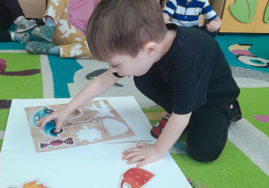 Chłopiec dopasowuje obrazek do kształtu na planszy