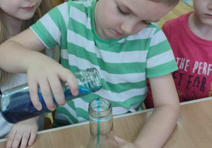 Chłopiec wlewa do butelki niebieski płyn
