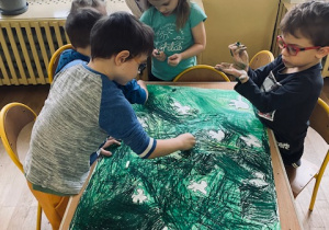 dzieci malujące zielonymi pastelami