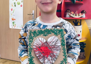 chłopiec pokazuje pracę plastyczną przedstawiającą serce
